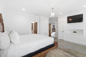 a white bedroom with a white bed and a tv at Emigrant's Inn in Fredericksburg +49 photos