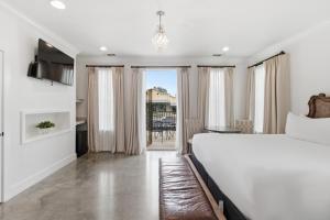 a bedroom with a large white bed and a balcony at Emigrant's Inn in Fredericksburg
