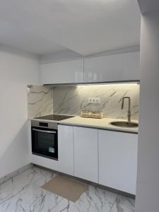 a white kitchen with white cabinets and a sink at Casa Tul Studio Apartment in Maspalomas