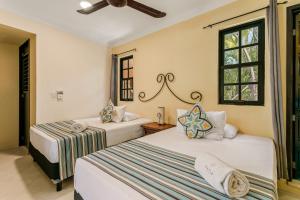 a bedroom with two beds and a window at Hotel Barrio Latino in Playa del Carmen
