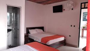 a bedroom with two beds and a tv on the wall at Hotel Rios in Garzón