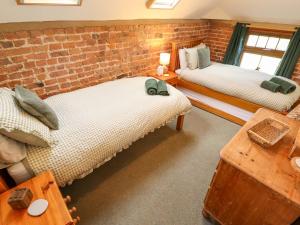two beds in a room with a brick wall at Barn Owl in Louth
