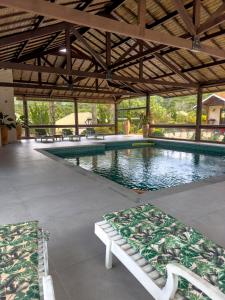 a swimming pool with benches in front of a building at Estalagem Mandeville in Monte Verde