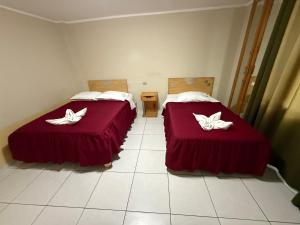 two beds in a room with red sheets and white towels at HOTEL LUCERO REAL Tacna in Tacna