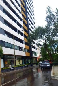 a building on a rainy street with cars parked in front at Golden in Cochabamba