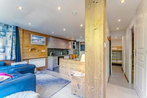 a living room with a blue couch and a kitchen at Spacious Ski-In Out apartment with Mountain Views in Val Thorens