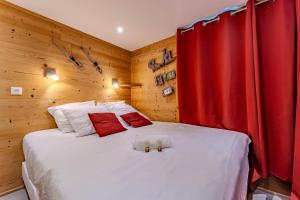 a bedroom with a large white bed with red curtains at Spacious Ski-In Out apartment with Mountain Views in Val Thorens