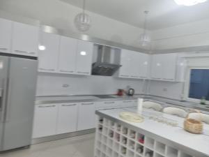 a white kitchen with white cabinets and a sink at Kalanar villa in Elbasan