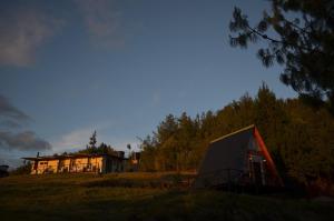 a house sitting on top of a grass field with a building at Tierra Viva By Astrid in Cucunubá