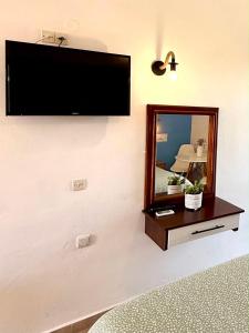 a flat screen tv on a wall with a mirror at Creta Star Apartments in Agia Galini