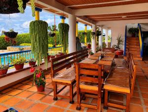 a restaurant with wooden tables and benches on a patio at Finca Hotel Vista Palmar - Eje Cafetero in Quimbaya