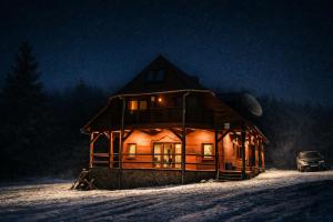 a large wooden cabin in the snow at night at Everwood Lodge, Transylvania in Sub Cetate