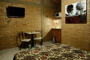 a bedroom with a bed and a table and a tv at Cabañas Yunyay in Villa Cura Brochero
