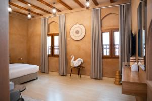 a bedroom with a bed and a swan on a chair at بيت المقصرة Almuqasrah house in Nizwa