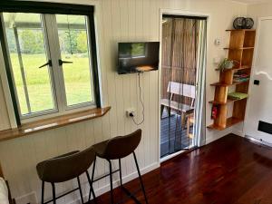 a room with two chairs and a television and a door at Bee Farm Off-Grid Tiny Home Stay in Tamaree