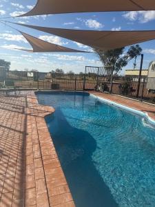 a swimming pool with an umbrella over it at Fossil Outpost Eromanga in Eromanga