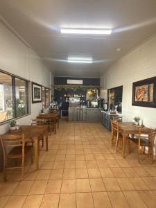 a dining room with wooden tables and a kitchen at Fossil Outpost Eromanga in Eromanga