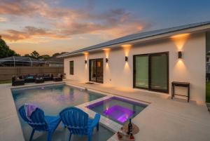 a swimming pool with two blue chairs and a house at Spacious home private pool patio & bbq in Vero Beach