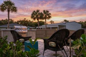 a group of chairs on a patio with palm trees at Spacious home private pool patio & bbq in Vero Beach