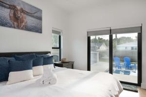 a bedroom with a large white bed with blue pillows at Spacious home private pool patio & bbq in Vero Beach +76 photos