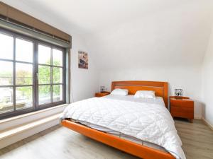 a white bedroom with a large bed and windows at Floribert in Nieuwpoort-Bad