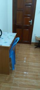 a table with a blue chair and a table and a door at Quyenhomestay in Cù Lao Tâu