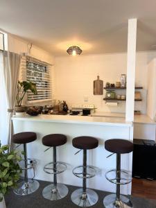 a kitchen with four bar stools in front of a counter at Central Nelson Townhouse in Nelson