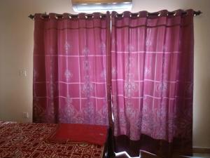 a pair of pink curtains in a room at Call it a home in Rawalpindi