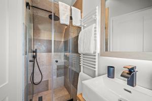a bathroom with a shower and a white sink at Traumloft Wenningstedt in Wenningstedt +6 photos