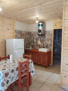 a kitchen with a table and a white refrigerator at Vista del Plata - Alojamiento in Potrerillos