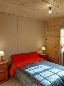 a bedroom with a bed with red sheets and two lamps at Vista del Plata - Alojamiento in Potrerillos