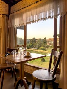 a dining room with a table and chairs and a window at Estalagem Mandeville in Monte Verde
