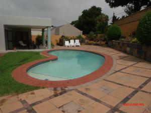 a swimming pool with a brick border in a yard at Spacious Garden Cottage in Johannesburg