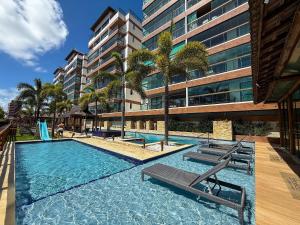 a swimming pool with chairs and a large building at Villas de Samoa - House with 4 bedrooms in Cabedelo