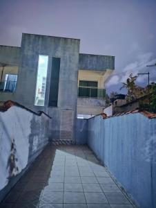 a building with a fence and a walkway at Casa aconchegante in Peruíbe