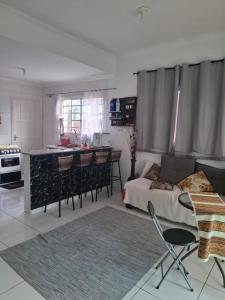 a living room with a bed and a kitchen at Casa aconchegante in Peruíbe