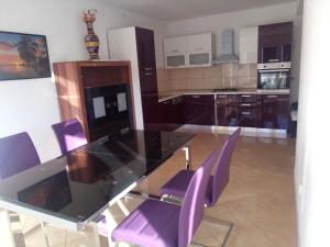 a kitchen with a glass table and purple chairs at Apartments Nikola in Pučišća