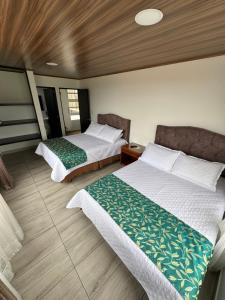 two beds in a hotel room with at Tauko Tú Casa in Paipa