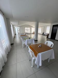 a cafeteria with tables and white chairs and windows at Tauko Tú Casa in Paipa