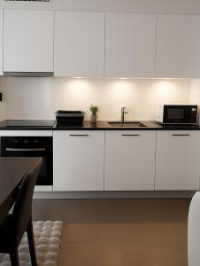 a kitchen with white cabinets and a sink at PepinA'S Home in Martigny-Ville
