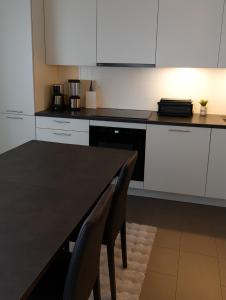 a kitchen with white cabinets and a black table and chairs at PepinA'S Home in Martigny-Ville