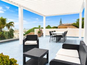 a patio with a table and chairs and a white pergola at Villa Dolce Vita in Triscina