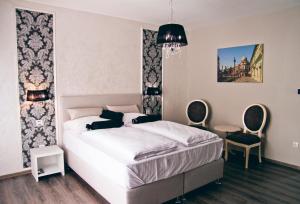 a bedroom with a white bed and two chairs at Hotel Bakarni Lonac in Brčko