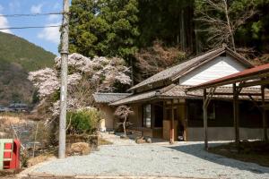 a house with a flowering tree in front of it at Nagi no Ne in Washika