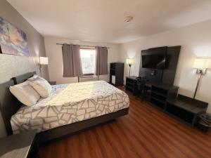 a hotel room with a bed and a flat screen tv at Best Nights Hotel in Fond du Lac