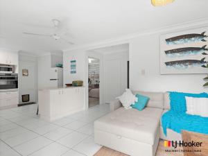 a white living room with a white couch and a kitchen at Barefoot by the Bay in Iluka +8 photos