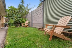 two chairs sitting in the grass next to a house at Barefoot by the Bay in Iluka