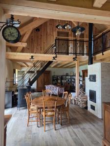 a dining room with a table and chairs and a clock at La R'mise de Surcey in Alaise