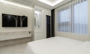 a white bedroom with a bed and a tv at Hotel Mayotte in Uiwang +15 photos