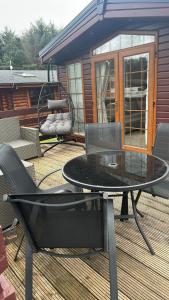 a glass table and chairs on a deck at Olive Tree Lodge in West Thirston
